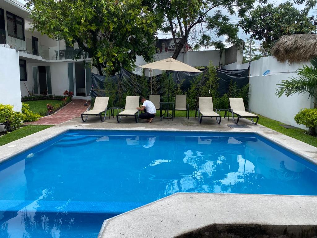 una piscina azul con sillas y sombrilla en Hotel fresno Xochitepec, en Chiconcuac