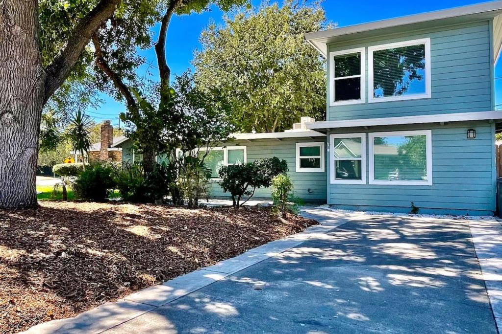 a blue house with a tree and a driveway at Uniquely styled home minutes to Downtown Sac! in West Sacramento
