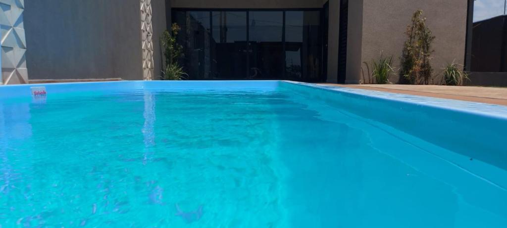 uma piscina com água azul em frente a uma casa em Beach House Olímpia - Casa Temporada em Olímpia
