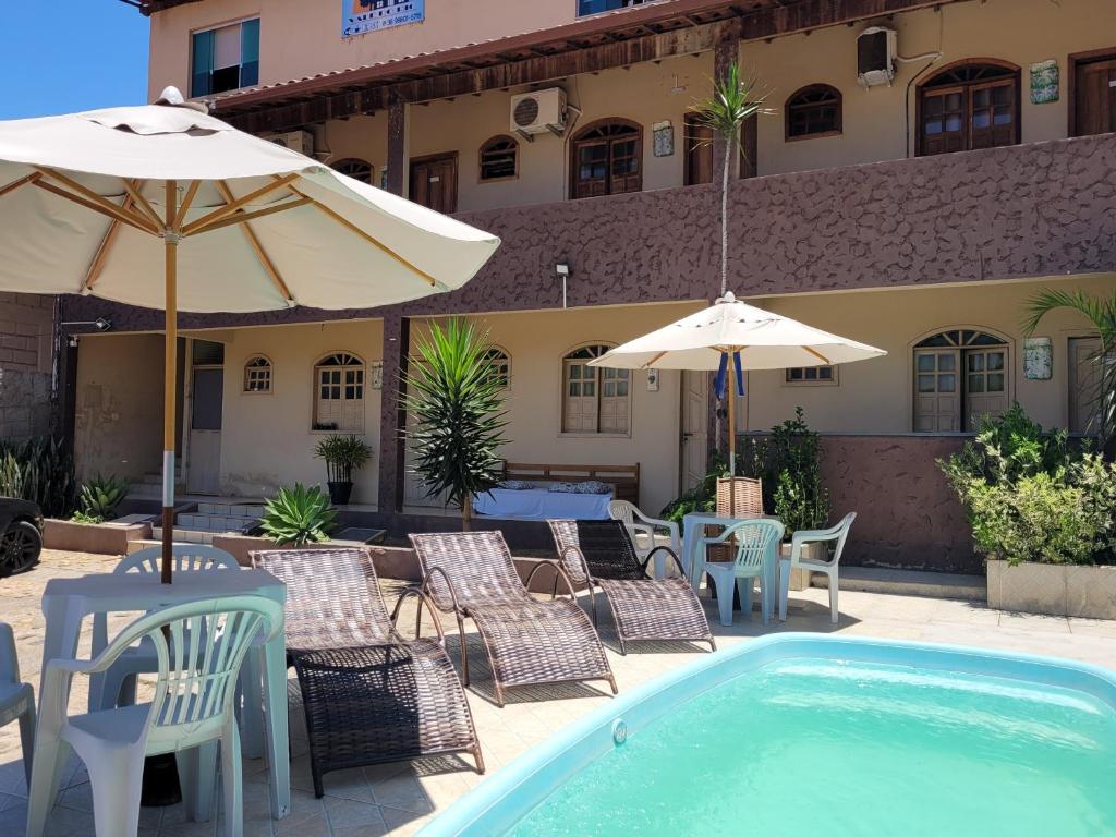 patio z leżakami i parasolami przy basenie w obiekcie Hotel Vale do Rio w mieście Três Marias