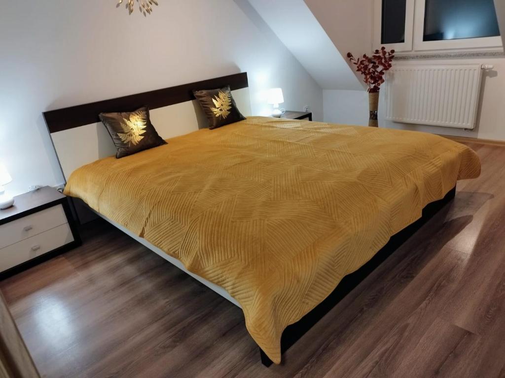 a bedroom with a large bed with a yellow bedspread at Apartament Marzenie 4 - Opole in Opole