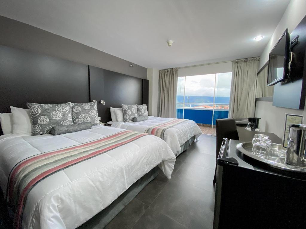 ein Hotelzimmer mit 2 Betten und einem großen Fenster in der Unterkunft Tibisay Hotel Boutique Mérida in Mérida