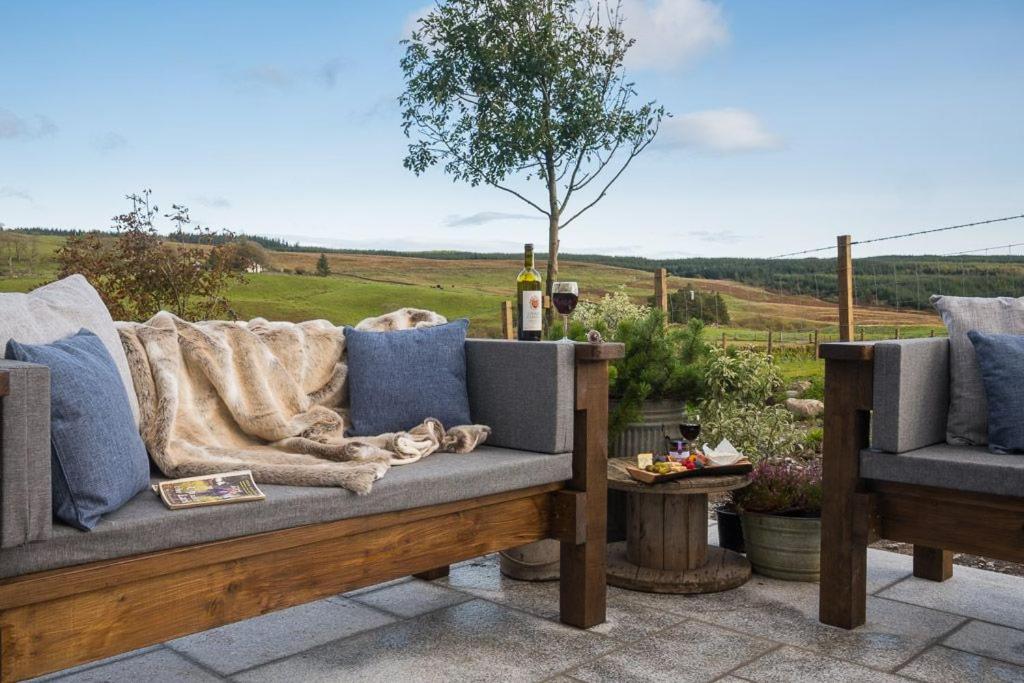 a couch on a patio with a view of a field at Dairy Cottage in Gatehouse of Fleet