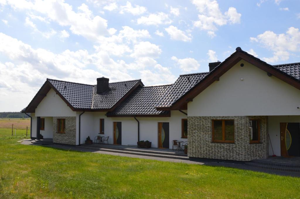 Biały dom z dachem na polu w obiekcie Agroturystyka Dom Skowronek w mieście Legbąd