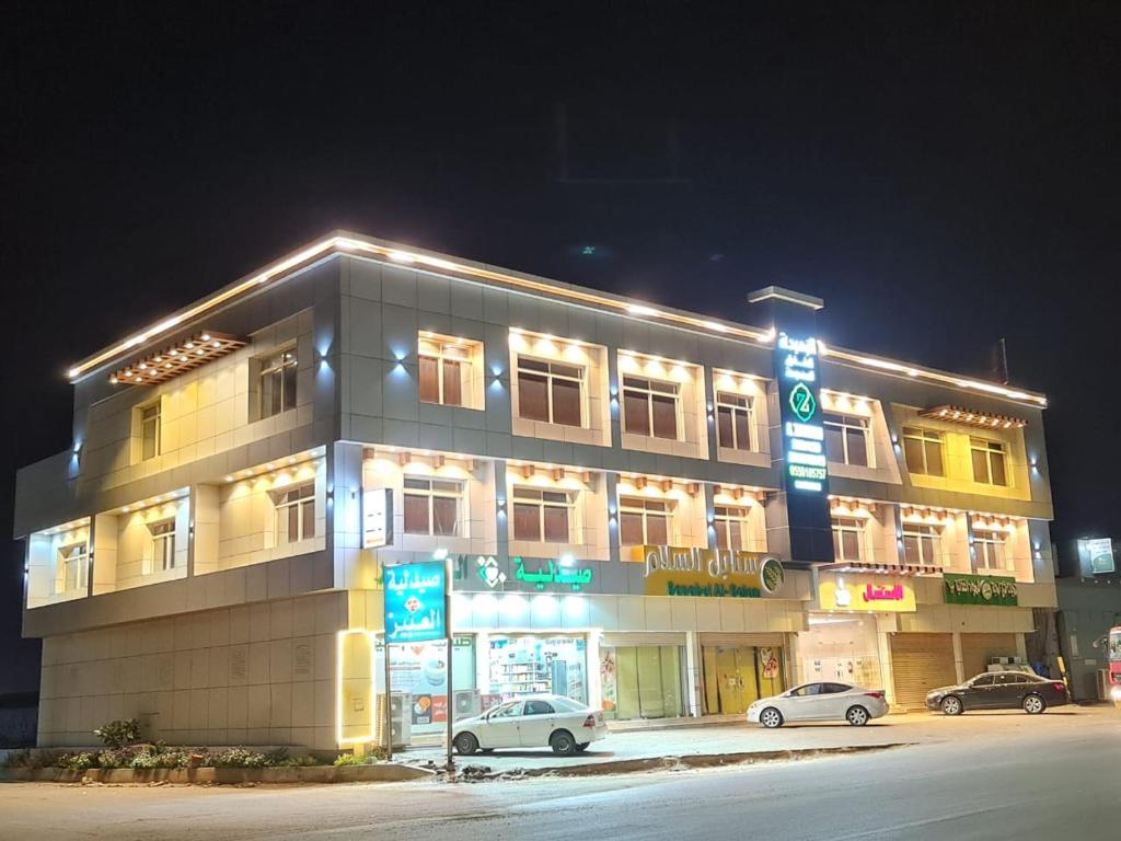 a large building with cars parked in front of it at الزمردة للشقق المخدومة in Ash Shuqayq