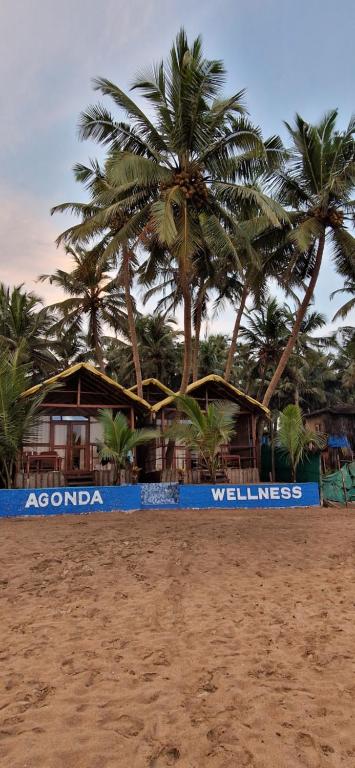um sinal numa praia com palmeiras ao fundo em Agonda Wellness em Agonda