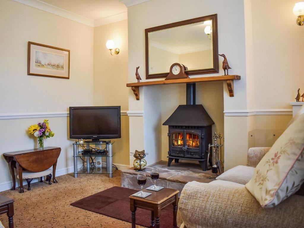 a living room with a fireplace and a tv at Ivy Cottage in Two Dales