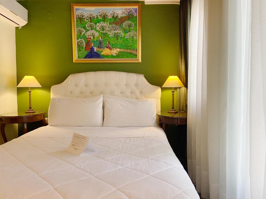 a bedroom with a white bed with a green wall at Five Seasons Pension in Nafplio