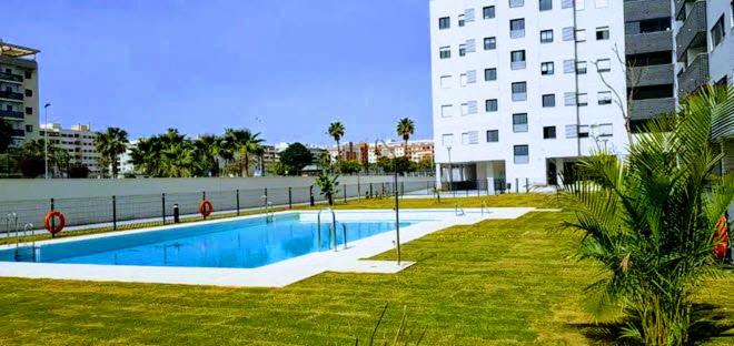 a swimming pool in front of a large building at Ático con Piscina y Vistas al Mar Parque Litoral in Málaga