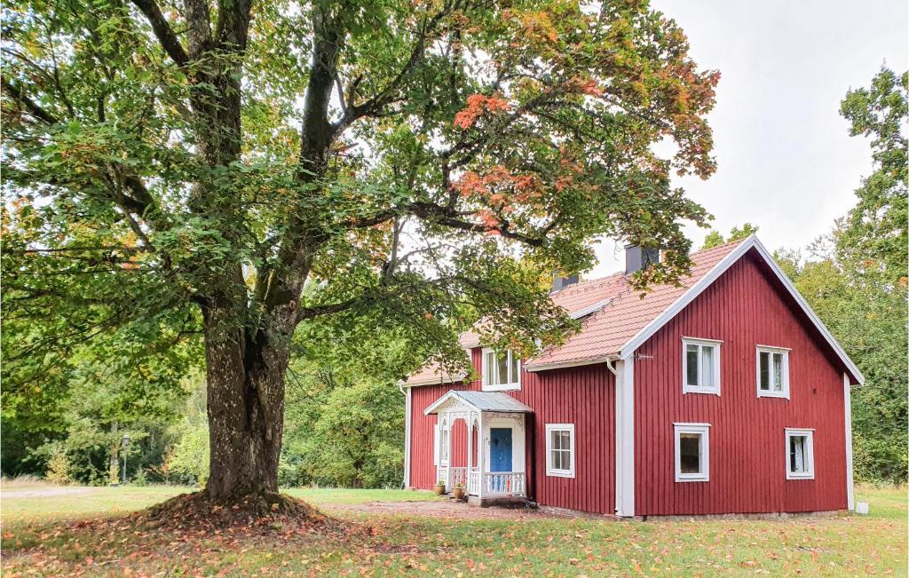 un granero rojo con un árbol delante de él en Beautiful Home In lmhult With Kitchen, en Älmhult