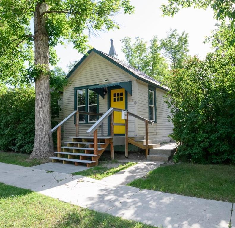 ein kleines Haus mit gelber Tür und Treppe in der Unterkunft Adorable and Cozy Bungalow in Great Falls