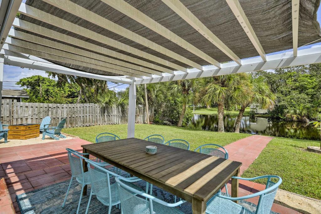 een houten tafel en stoelen onder een witte pergola bij Merritt Island Home Fire Pit and Canal Access! in Merritt Island