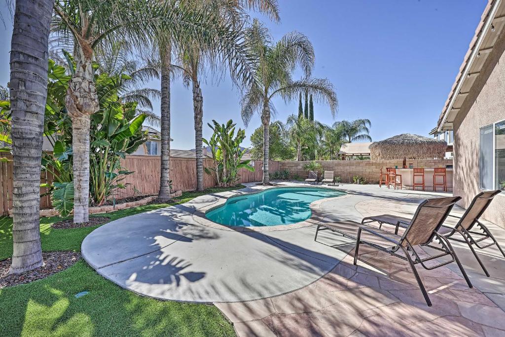 a swimming pool with two chairs and palm trees at Incredible Wildomar Getaway with Outdoor Oasis! in Wildomar