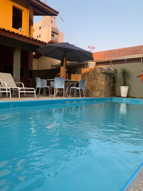 einen Pool mit einem Tisch und einem Sonnenschirm in der Unterkunft Lindo Sobrado Amarelo -próximo a praia in Mongaguá