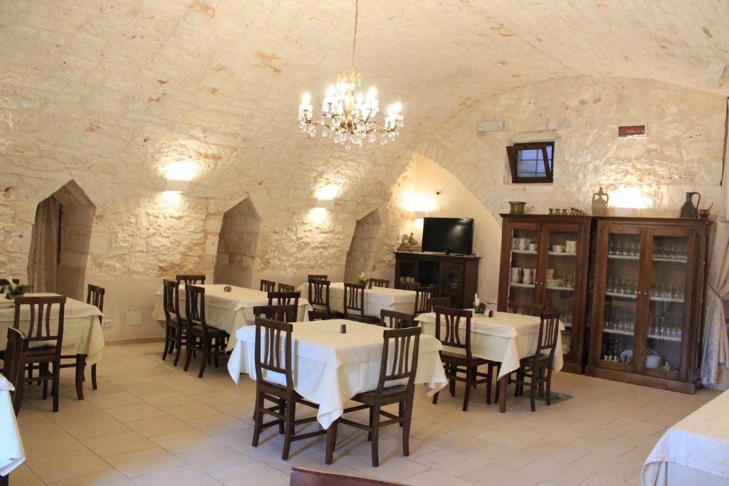 a dining room with tables and chairs and a chandelier at Masseria Valente in Ostuni