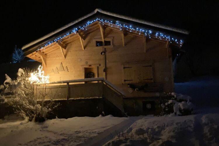 a house with christmas lights on the side of it at Cosy chalet with garden in Notre-Dame-de-Bellecombe