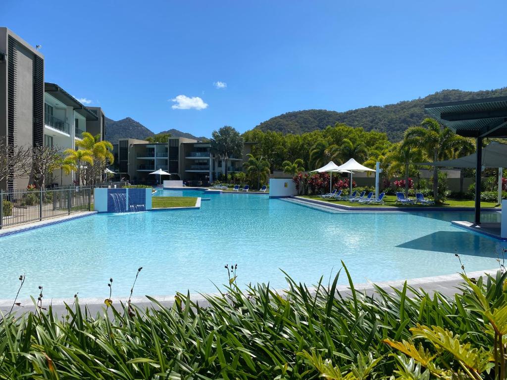 a large blue swimming pool with mountains in the background at Blue on Blue Deluxe King or Twin room, steps from ferry, amazing pool, wifi in Nelly Bay