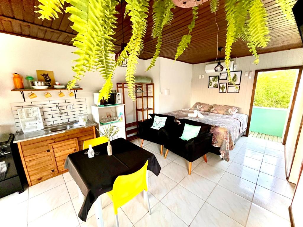 a bedroom with a bed and a table and yellow chairs at Bella Vista Kitnets in Farol de Santa Marta