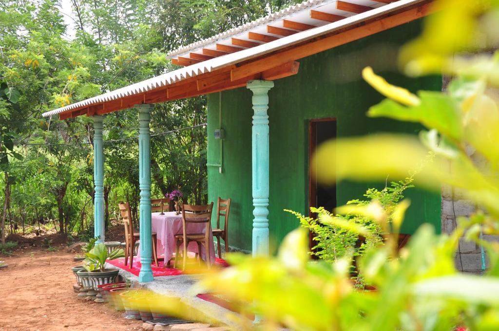 a green house with a table in front of it at Organic farm Wish Prabha lake view homestay in Sigiriya
