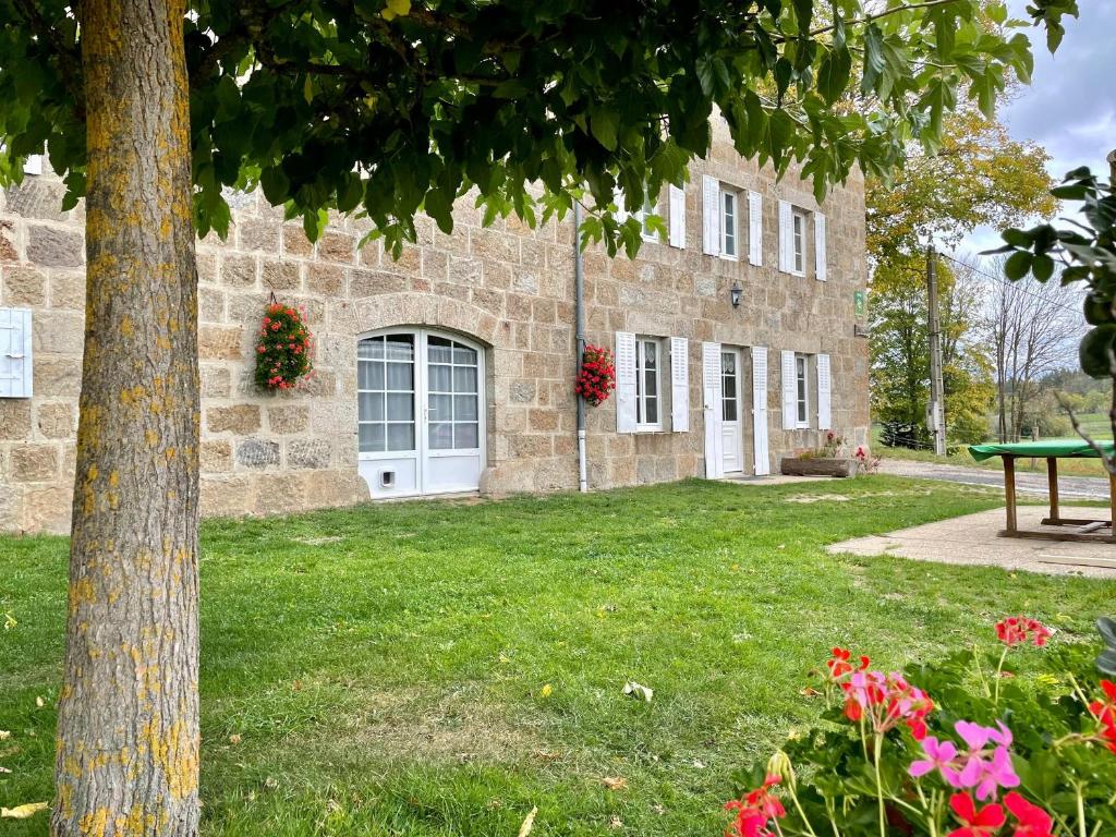 a stone building with a tree and flowers in the yard at Gîte Saint-Jeures, 5 pièces, 8 personnes - FR-1-582-254 in Saint-Jeures