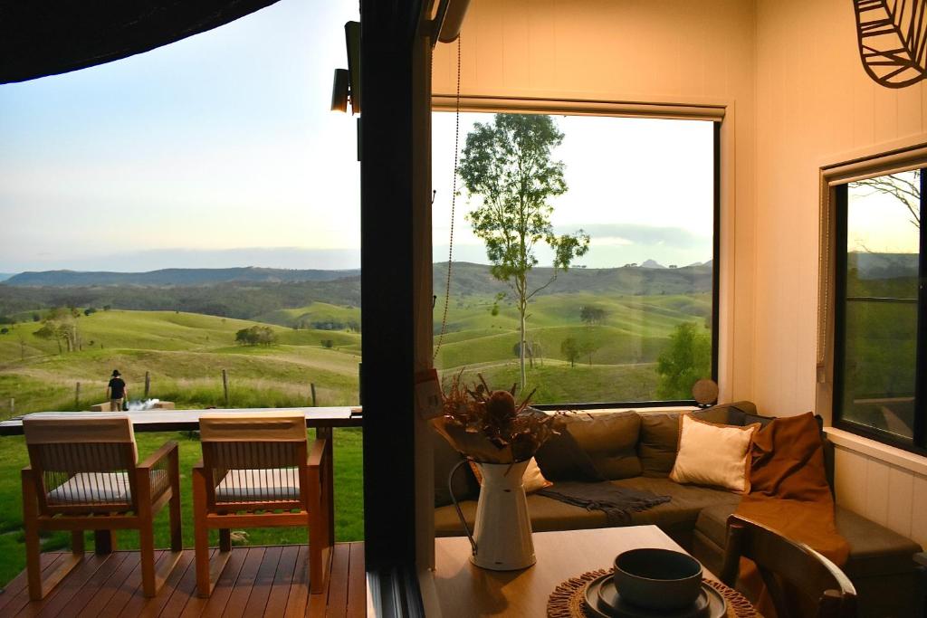 a living room with a couch and a large window at Ketchup's Bank Glamping in Boonah