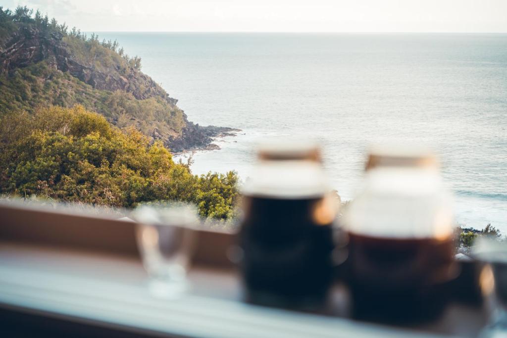 Duas garrafas de cerveja numa varanda com vista para o oceano em Le Coin d'Azur em Petite Île