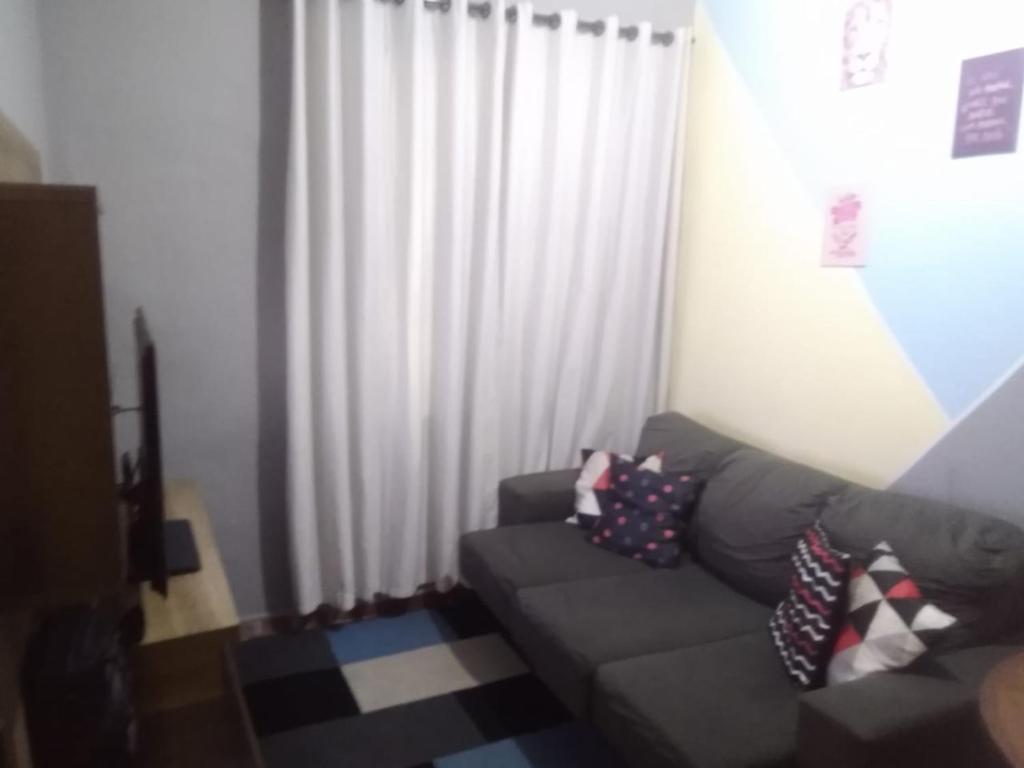 ein Wohnzimmer mit einem Sofa und einem weißen Vorhang in der Unterkunft Praia Grande Apartamento Aconchegante pertinho da Praia - 300m in Praia Grande