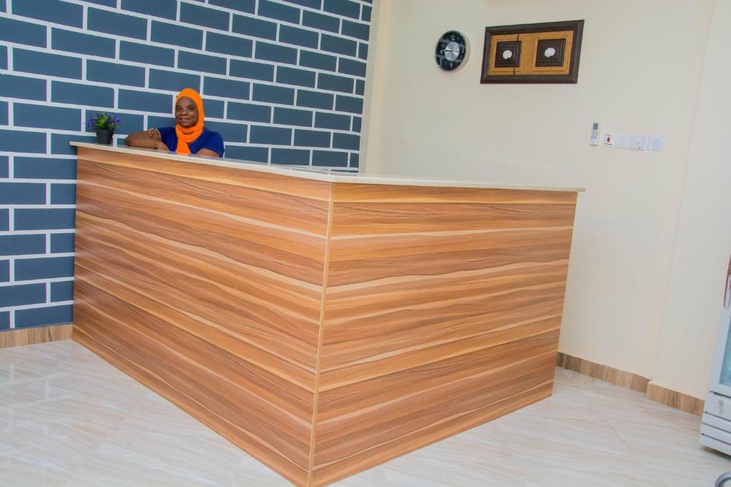 a woman standing behind a wooden counter in a room at GIDI LODGE in Tamale