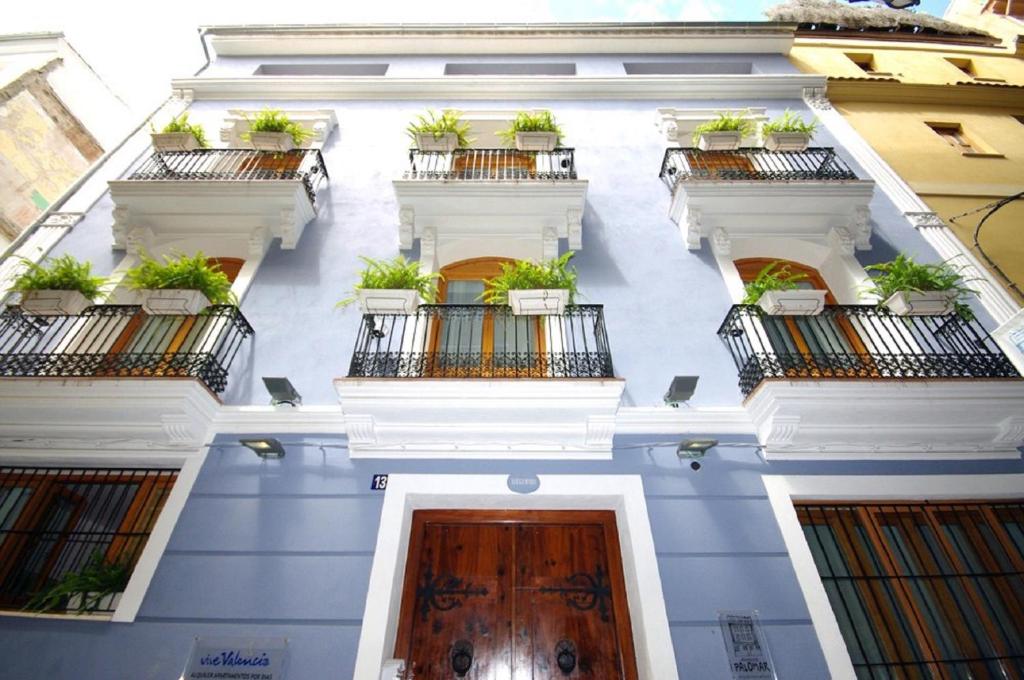 a white building with potted plants on the balconies at Edificio Palomar - PalomarGroup in Valencia