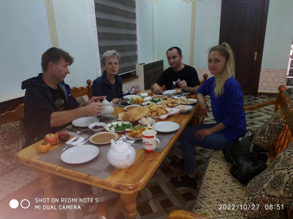 een groep mensen die rond een tafel eten bij Shayx Jalol in Bukhara