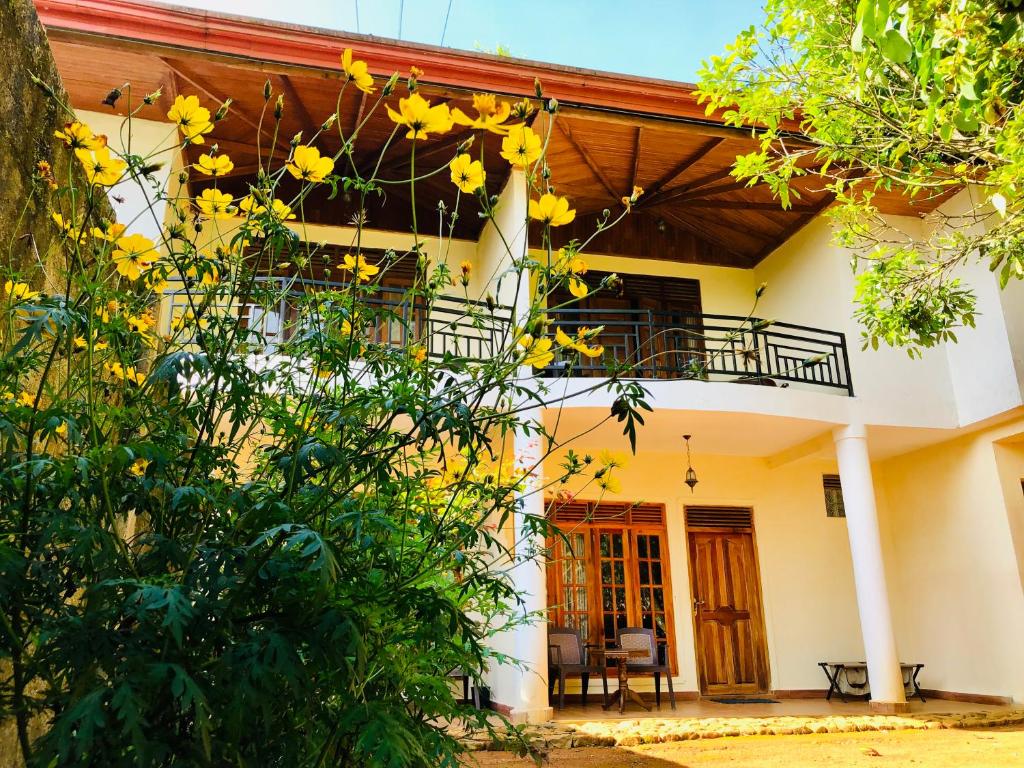 a house with yellow flowers in front of it at Hotel mango tree nearest Adam's peak in Adams Peak