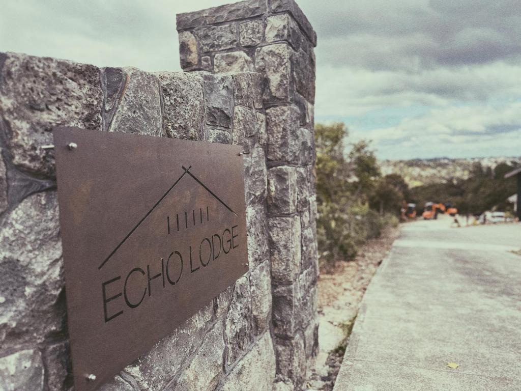 a sign on the side of a stone wall at Echo Lodge in Auckland