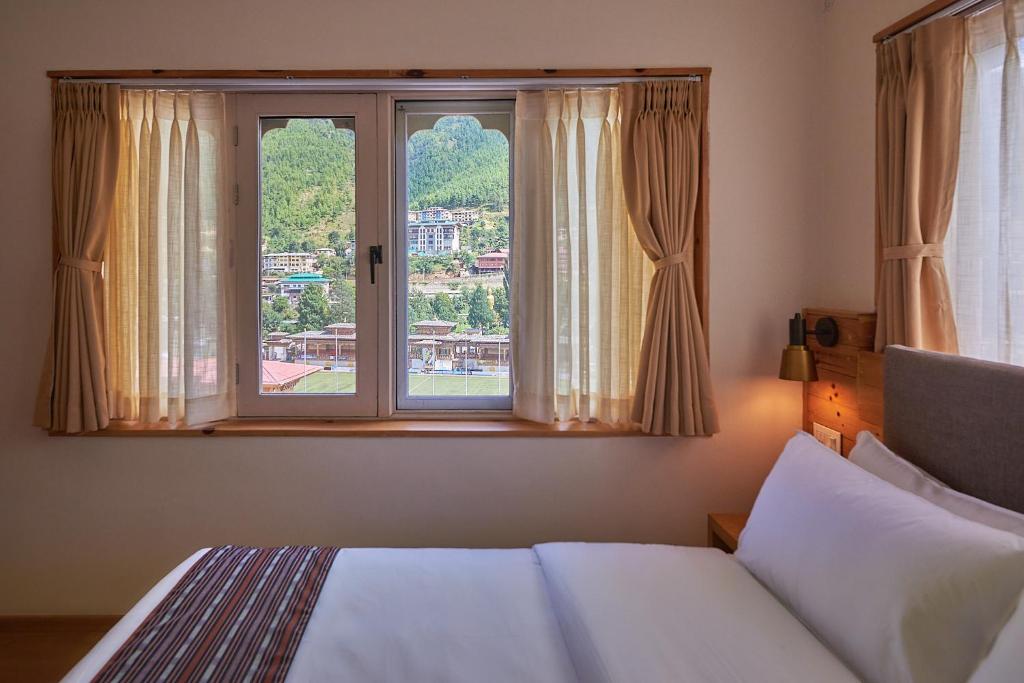 a bedroom with a bed and a large window at The Willows Hotel, Bhutan in Thimphu
