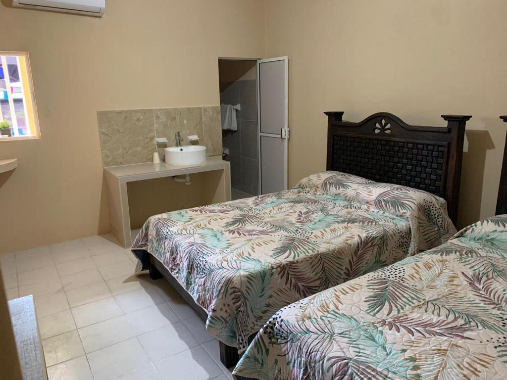 een slaapkamer met 2 bedden en een wastafel. bij Casa de los abuelos in Salina Cruz