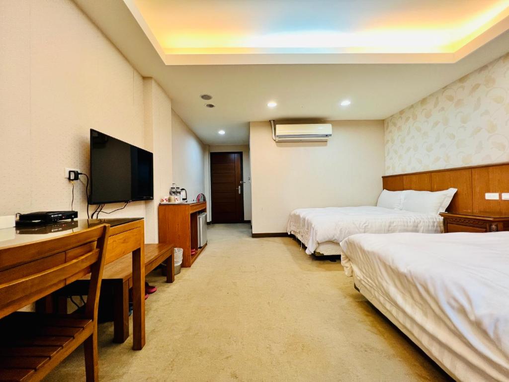 a hotel room with two beds and a flat screen tv at Mucha Boutique Hotel in Yilan City
