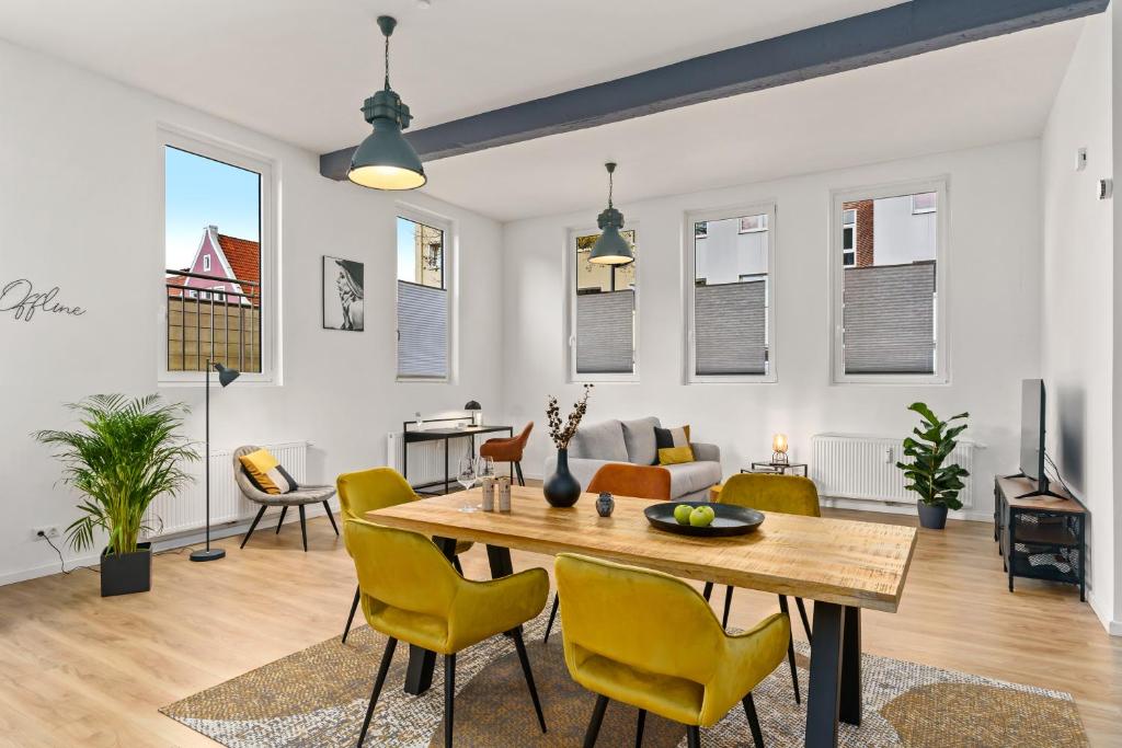 a living room with a wooden table and yellow chairs at MEL&BENS Loft-Appartements Terrasse Weserstadion in Bremen