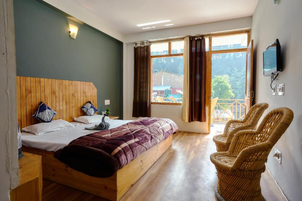 1 dormitorio con 1 cama y 2 sillas de mimbre en The Mad King's House & Cafe, en Manali