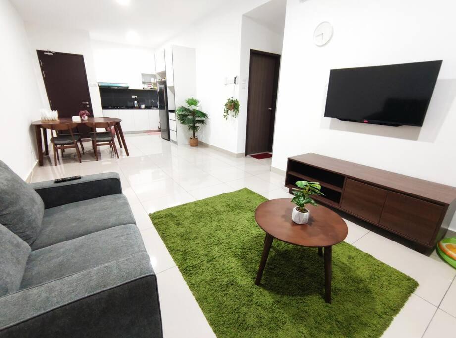 sala de estar con sofá, mesa y TV en Cikgukay Desaru Homestay Apartment With Pool View WiFi & Netflix, en Bandar Penawar