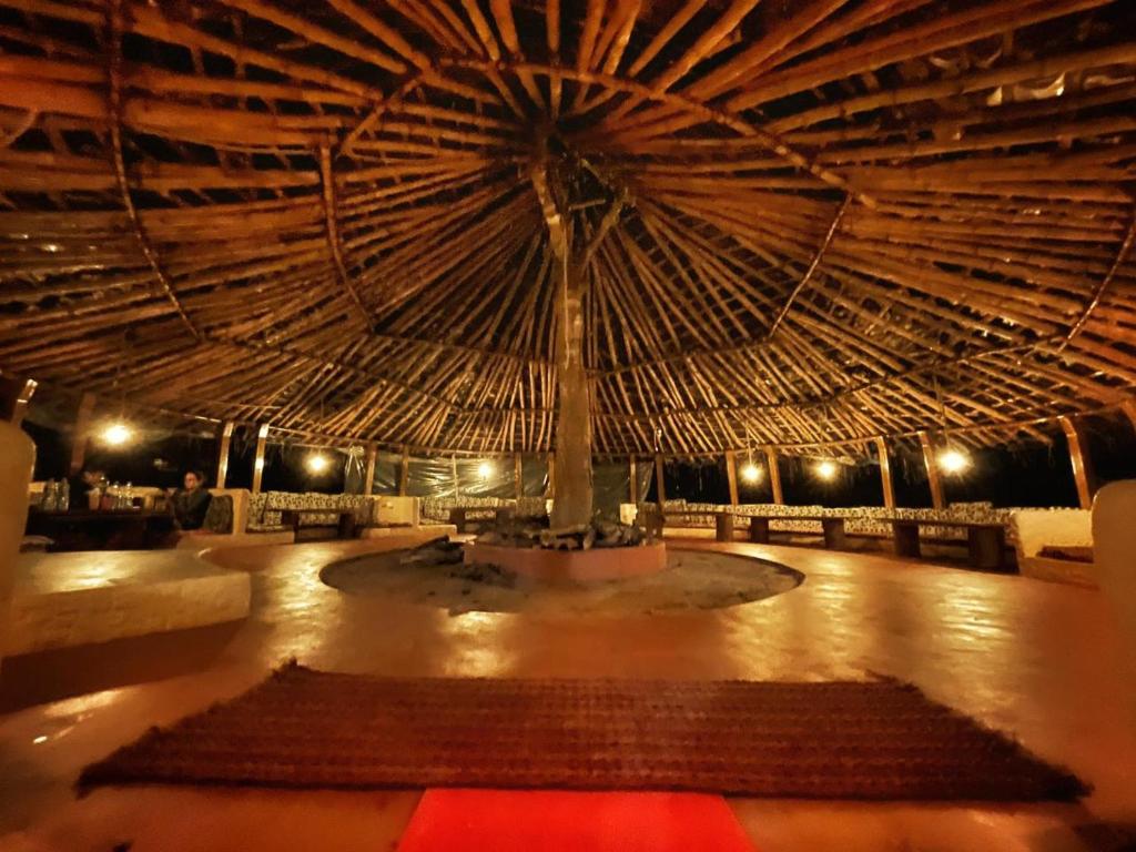 a large room with a large straw roof at StoneAge Resort Sakleshpur in Sakleshpur