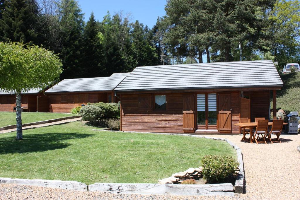 a log cabin with a table and chairs in front of it at Volcans Vacances Les Chalets Du Lac in Aydat