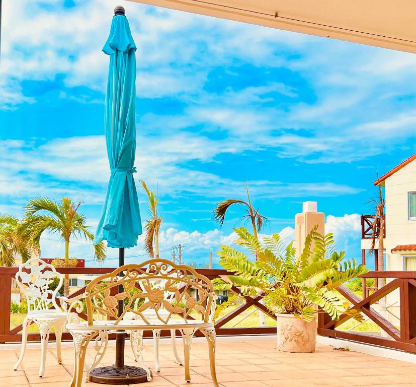 a patio with a blue umbrella and a table and chairs at Palm Villa Ishigakijima karei in Ishigaki Island