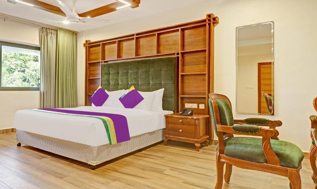ein Schlafzimmer mit einem Bett und einem Stuhl in der Unterkunft Treebo Tryst Vahada in Alappuzha
