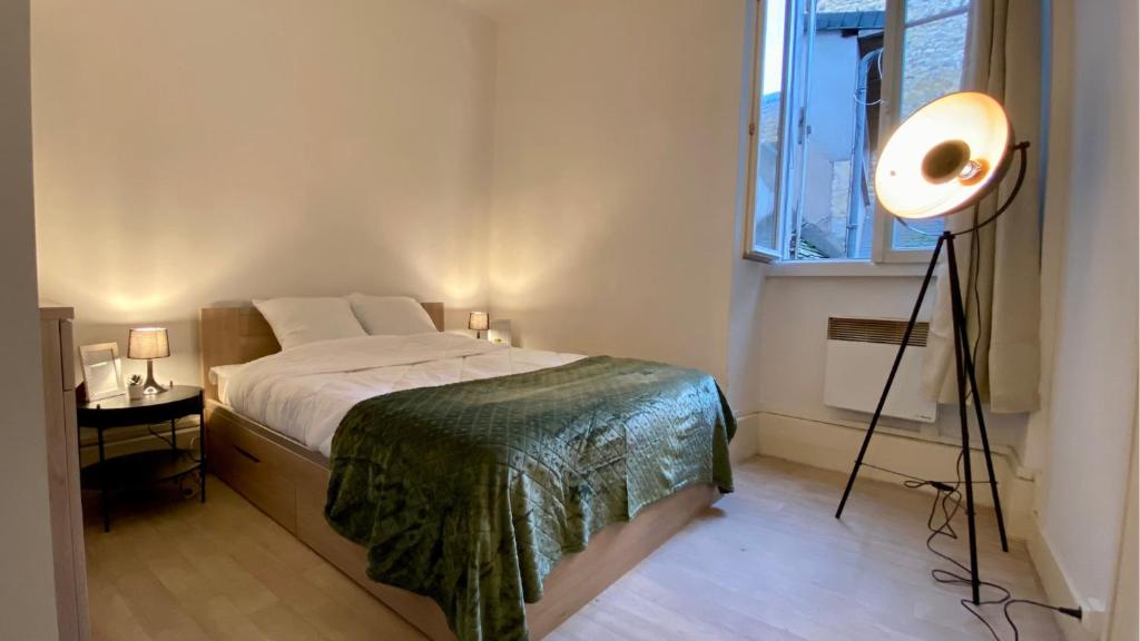 a bedroom with a bed and a lamp and a window at Le Chapitre in Nevers