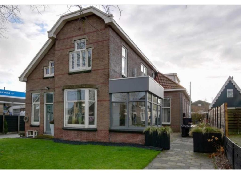 Casa de ladrillo marrón con ventanas blancas y césped verde en BNBSpanbroek, en Spanbroek