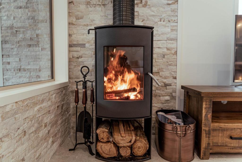 a stove with a fire in a room at Bruny Island Oceanfront Luxe Cabin with Spa in Adventure Bay