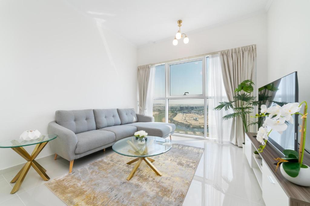 uma sala de estar com um sofá e uma grande janela em Immaculate 1BR apartment at Carson C em Dubai