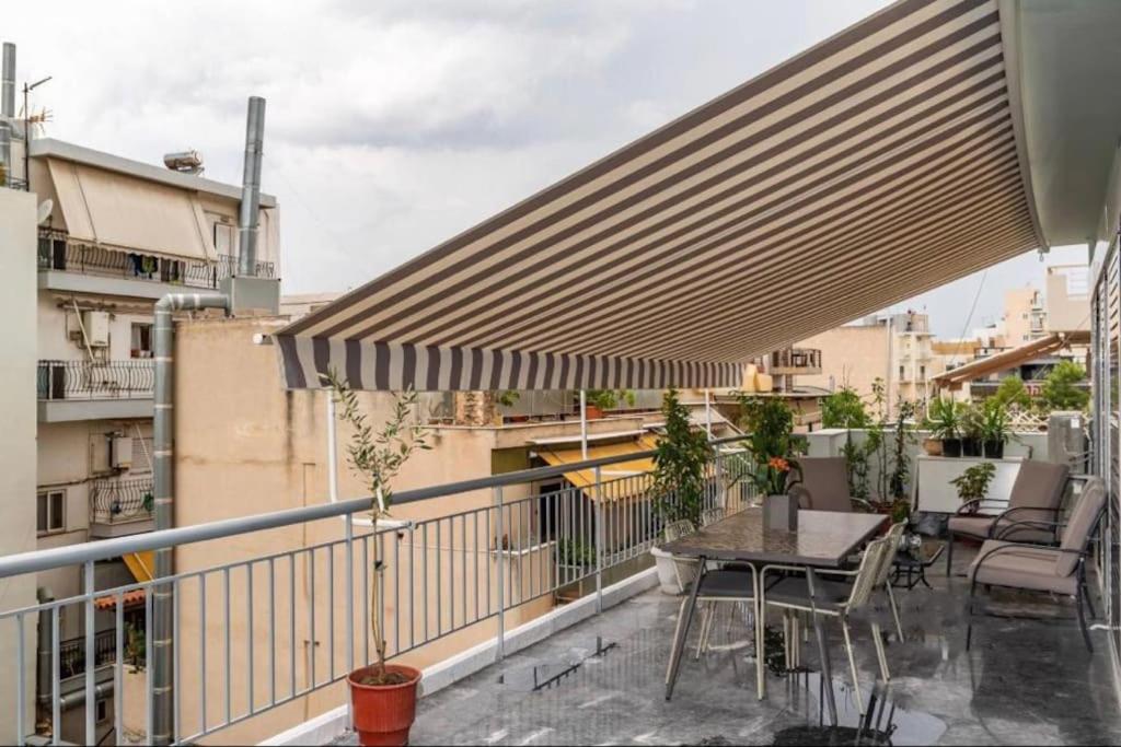 a patio with a table and chairs on a balcony at Artistic apt in vibrant Gazi with large terrace by GHH in Athens