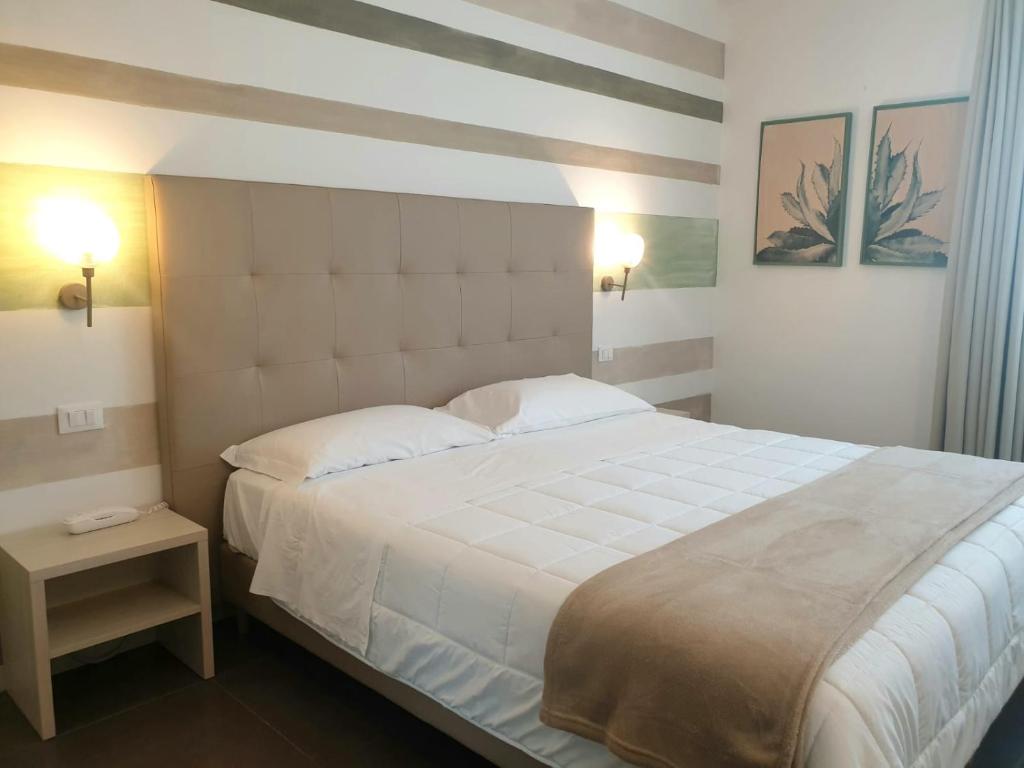 una camera da letto con un grande letto bianco con due cuscini di Hotel Grel a Chiaramonte Gulfi