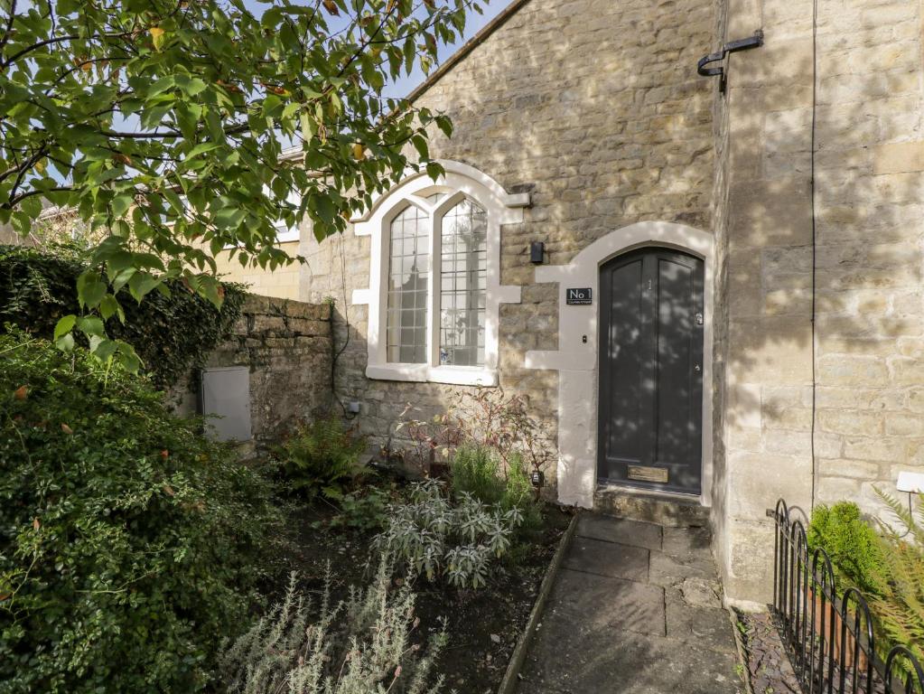 a brick house with a black door and a window at 1 Countess Chapel in Bath