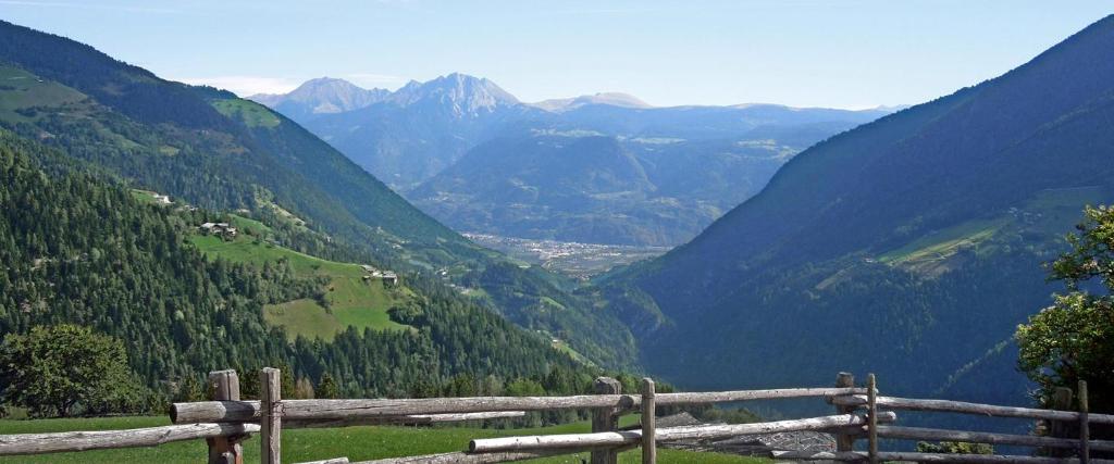 una valla de madera con vistas a un valle de montaña en Ferienwohnung Maiernhof Bauernhof Ultental, en San Pancrazio